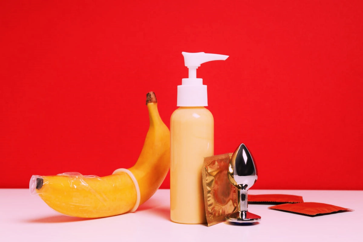 Lubricant, banana and condoms on a red background. 